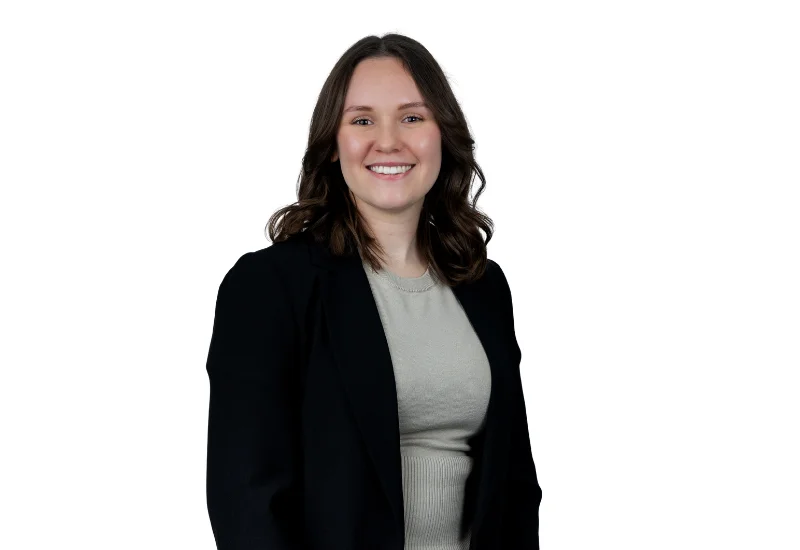 Professional headshot of a smiling woman with long brown hair wearing a black blazer, facing the camera.